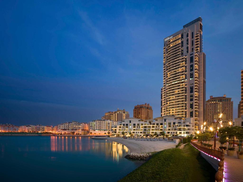 un grande edificio accanto a un corpo idrico di Hilton Doha The Pearl a Doha