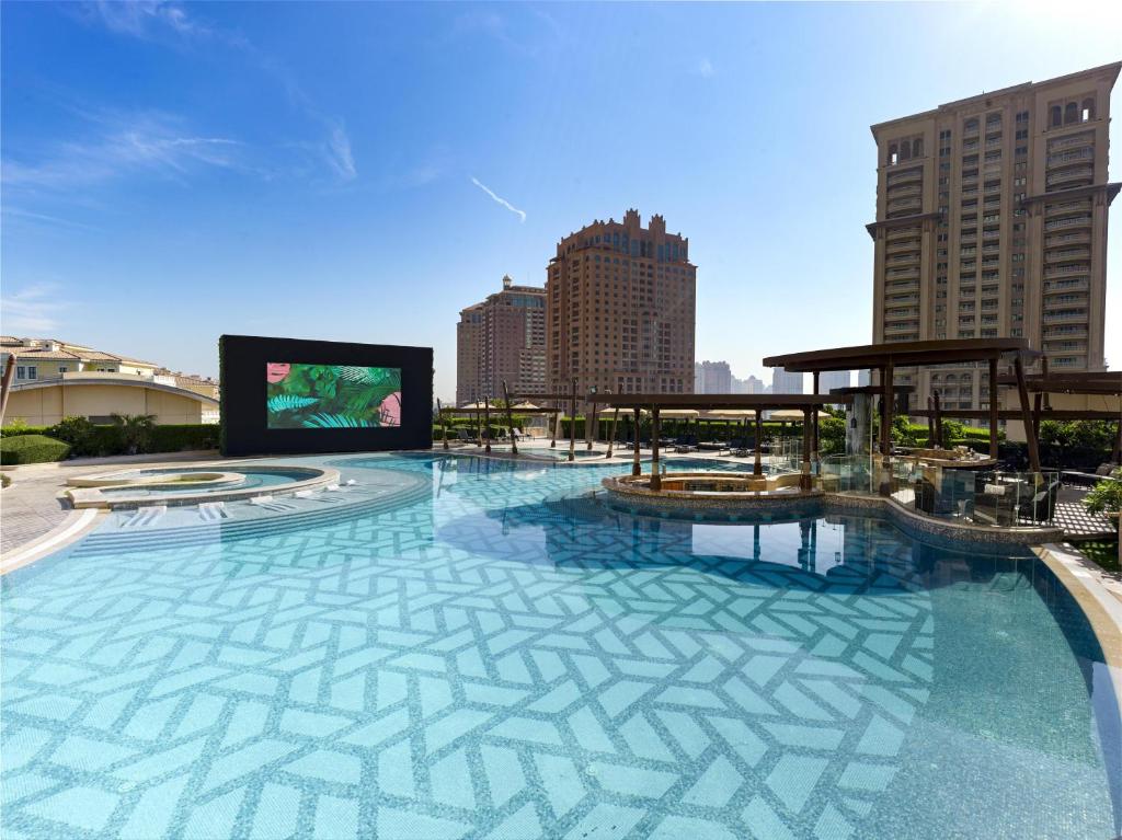 una grande piscina con uno schermo in una città di Hilton Doha The Pearl a Doha
