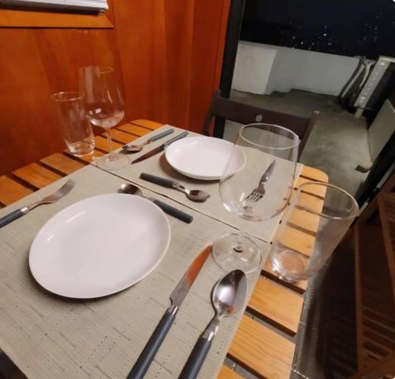 a table with two white plates and glasses on it at Itaewon Namsan View Rooftop in Haebangchon in Seoul