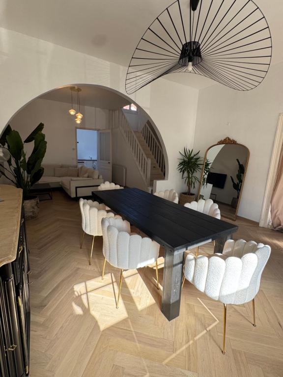 a dining room with a black table and white chairs at Maison de 140m2 à 300m de la plage in Dunkerque