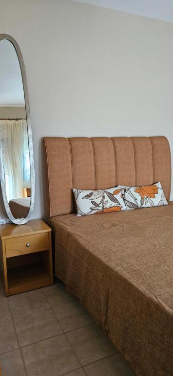 Una gran cama marrón con un espejo y una mesa. en Ampeli Garden, en Afitos