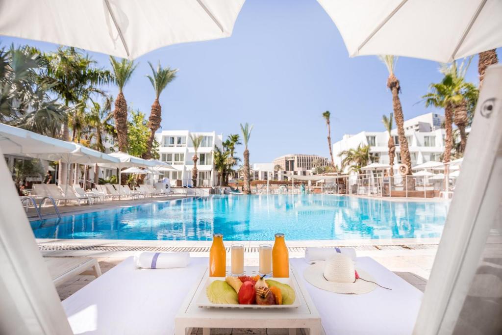 a table with a plate of fruit next to a swimming pool at Astral Palma Hotel in Eilat