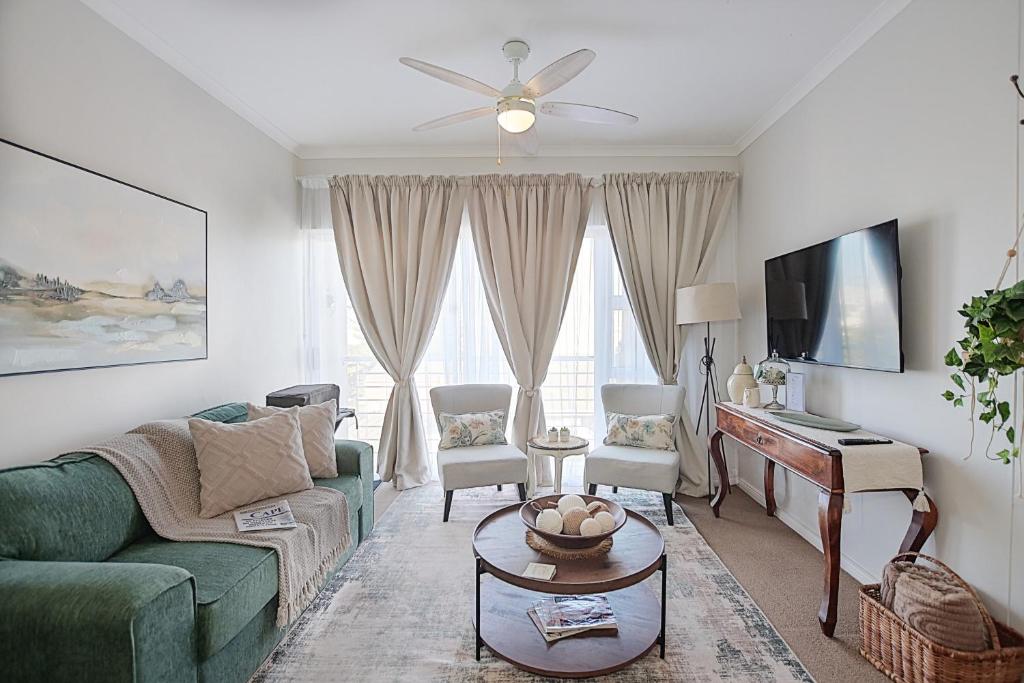 a living room with a green couch and a piano at Unwind at Coral Bright 2BR Beach Apartment in Bloubergstrand