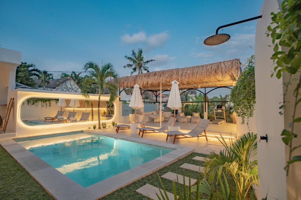 une piscine dans un complexe hôtelier avec chaises et parasols dans l'établissement Villa Nair NEW stylish 3BR Canggu with large pool, projector & green field view, à Canggu