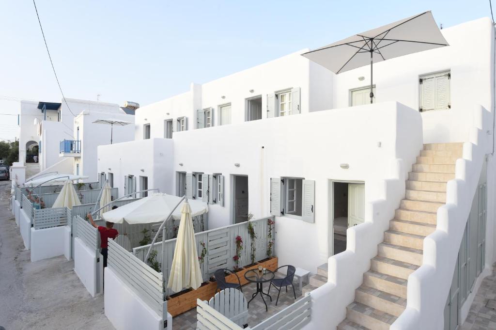 un edificio blanco con escaleras, mesas y sombrillas en Porto Naoussa, en Naousa