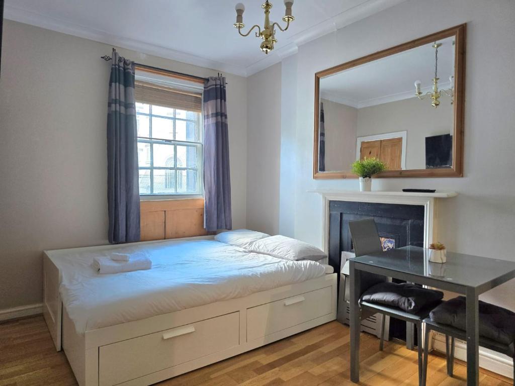 a bedroom with a bed with a mirror and a desk at Piccadilly West End Studio in London
