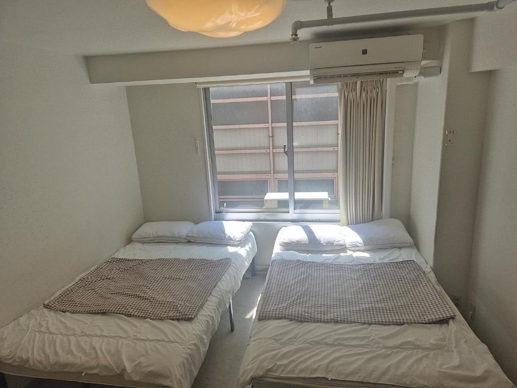 three beds in a room with a window at 1008 本町駅徒歩3分インペリアル快適ルーム 最大6名 in Osaka