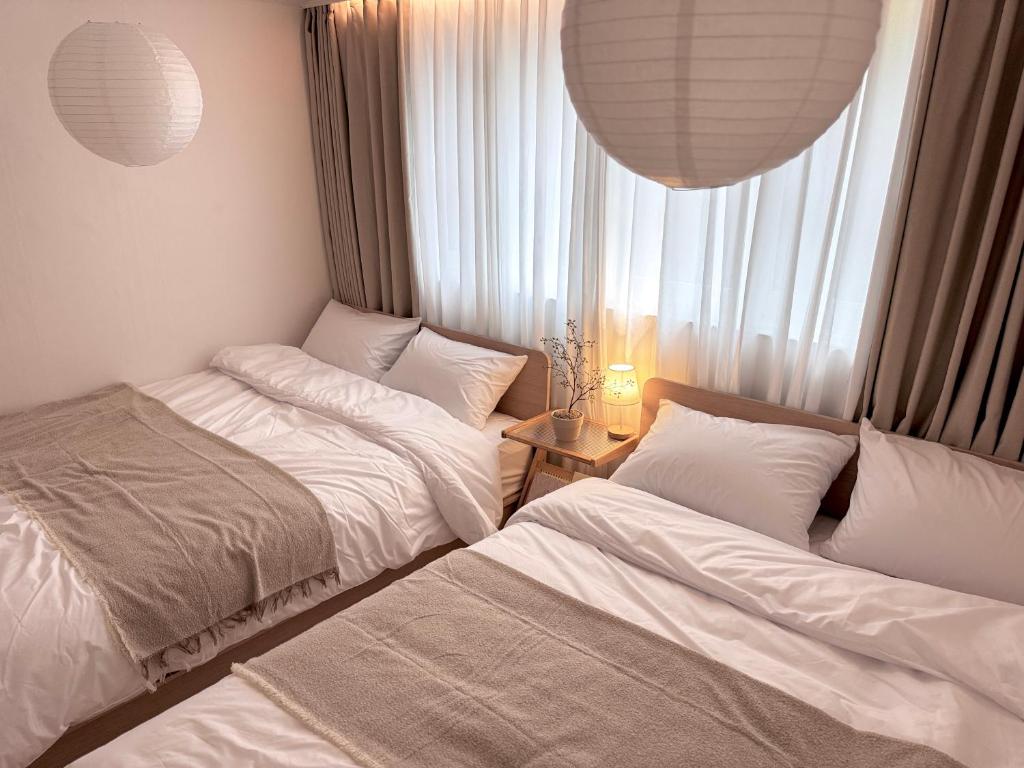 two beds in a small room with a window at Song-i stay & in Seoul