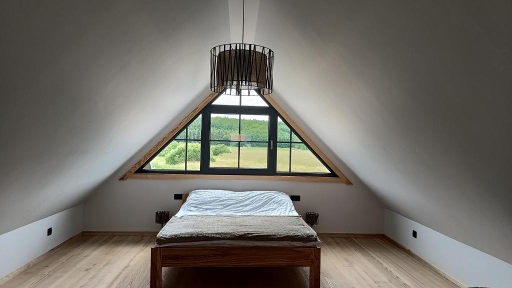 ein Bett in einem Zimmer mit einem großen Fenster in der Unterkunft Drewno i Len in Debina