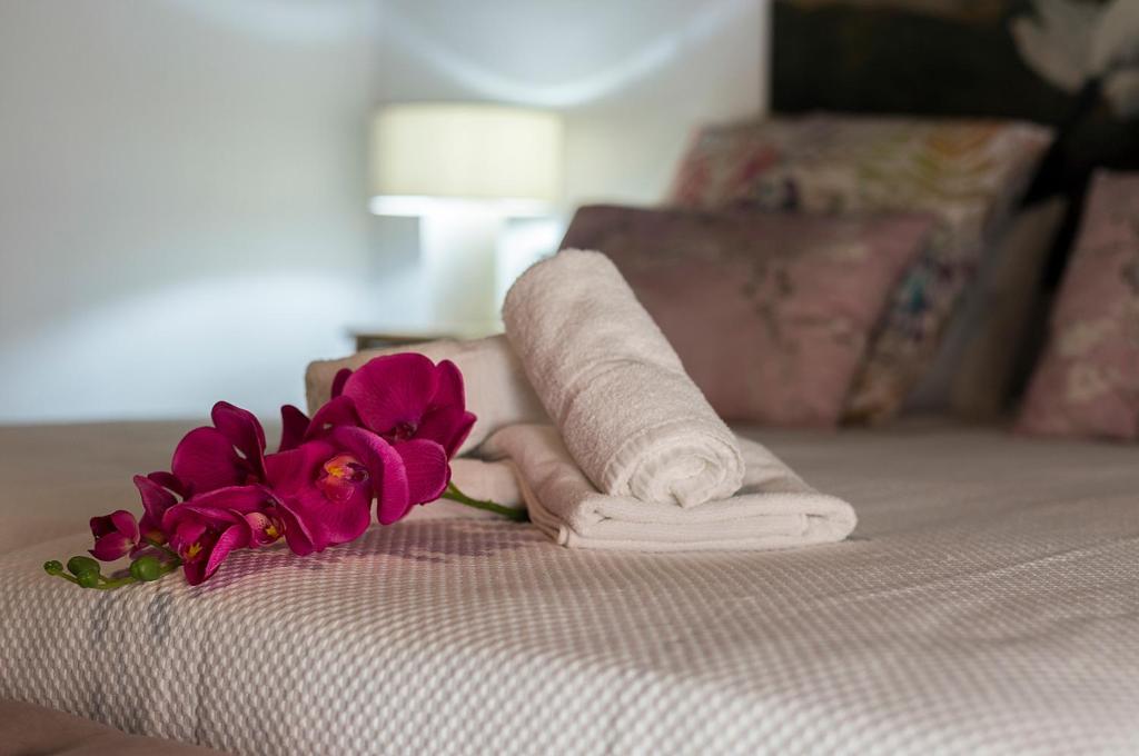 a rolled up towel and flowers on a bed at Duplex Los Corceles Casa Palacio in Jerez de la Frontera
