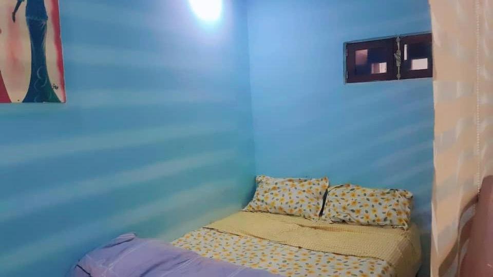 un piccolo letto in una camera con parete blu di Résidence SKS Hébergement a Dakar