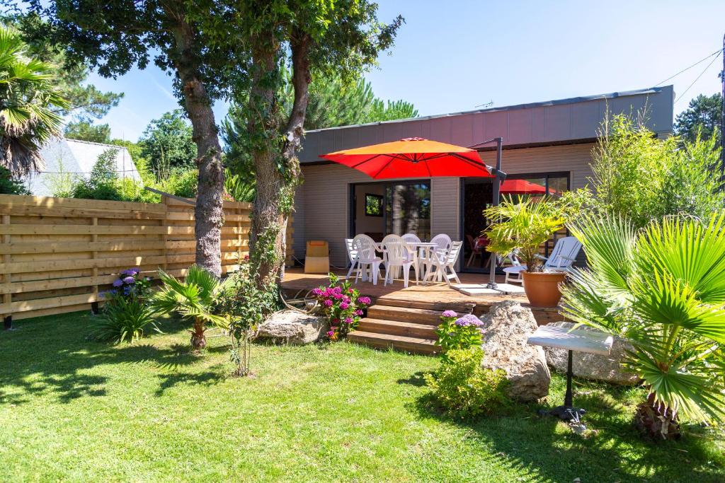 a backyard with a patio with a red umbrella at Villa Léonie in Trégunc