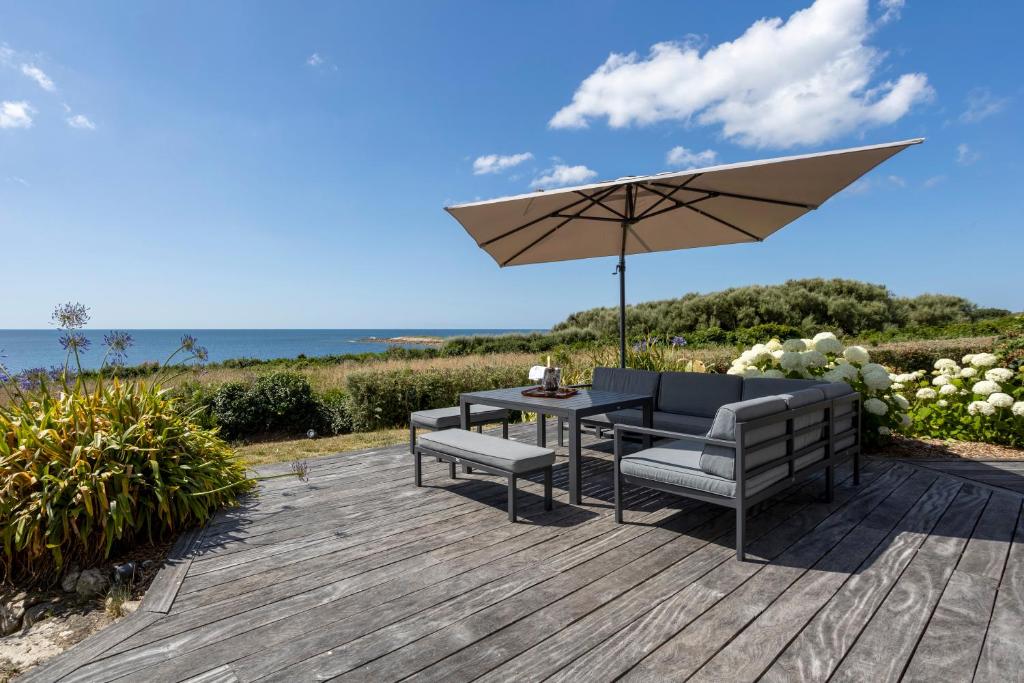 une terrasse en bois avec une table et un parasol dans l'établissement Magnifique villa accès direct plage, à Audierne