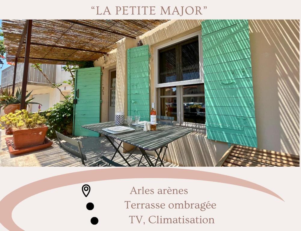 une terrasse avec une table et une maison verte dans l'établissement La petite Major Arles centre, à Arles