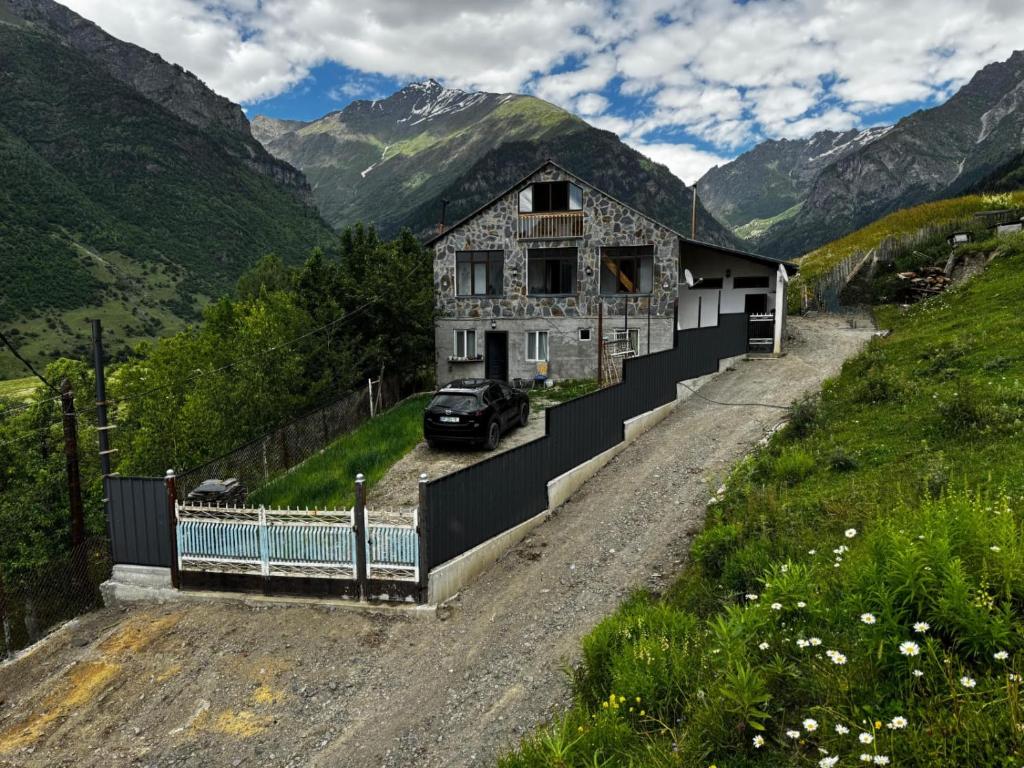 a house on a dirt road in the mountains at Farielli Guesthouse in Mestia