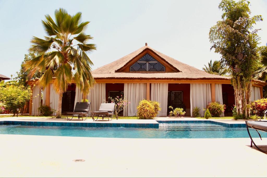 a house with a swimming pool in front of a house at Villa Épuré Tribale in Darou Rhamane