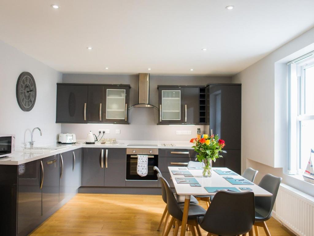 una cocina con armarios negros y una mesa con sillas en 2 Bed in TENBY FB284, en Tenby