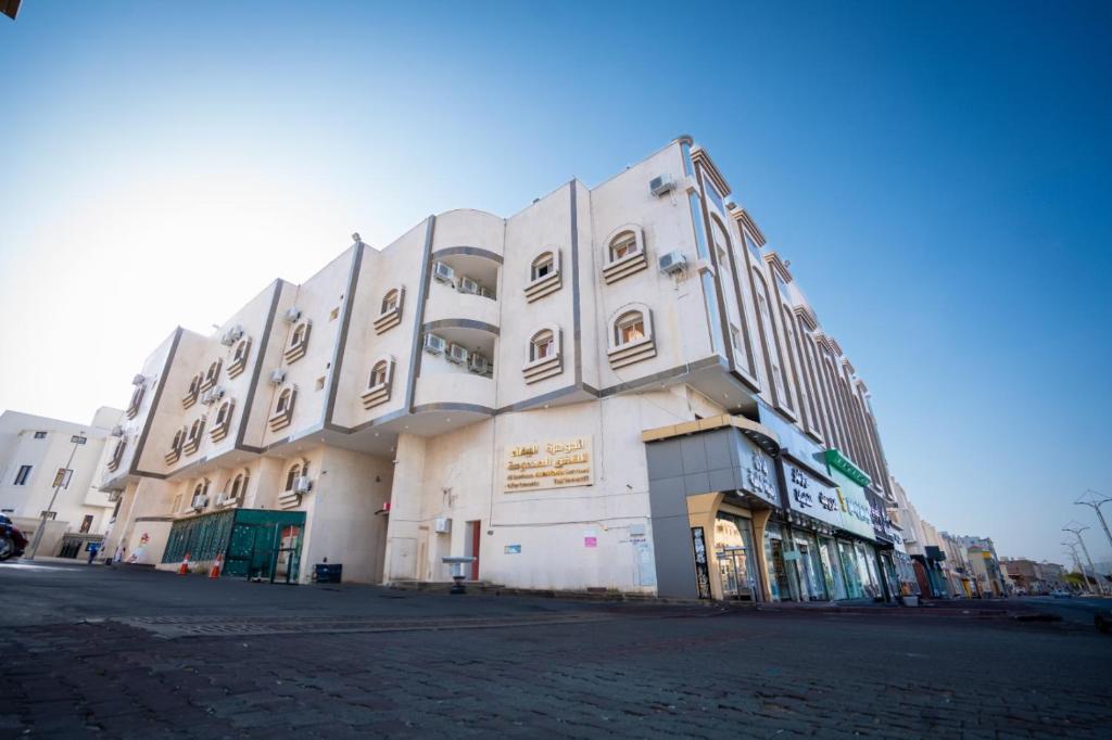 a large white building on the side of a street at الجوهرة البيضاء للشقق المخدومة in Taif