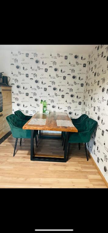 a table and two green chairs in front of a wall at FeWo - Heinsberg-Dremmen in Heinsberg