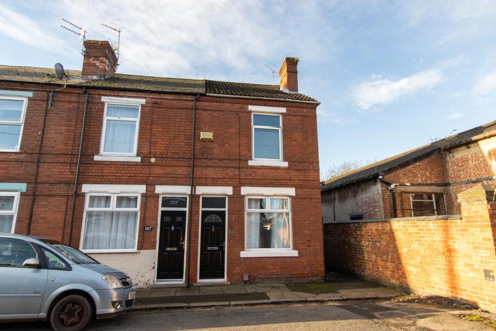 a brick house with a car parked in front of it at K Suites - Granville Avenue in Long Eaton