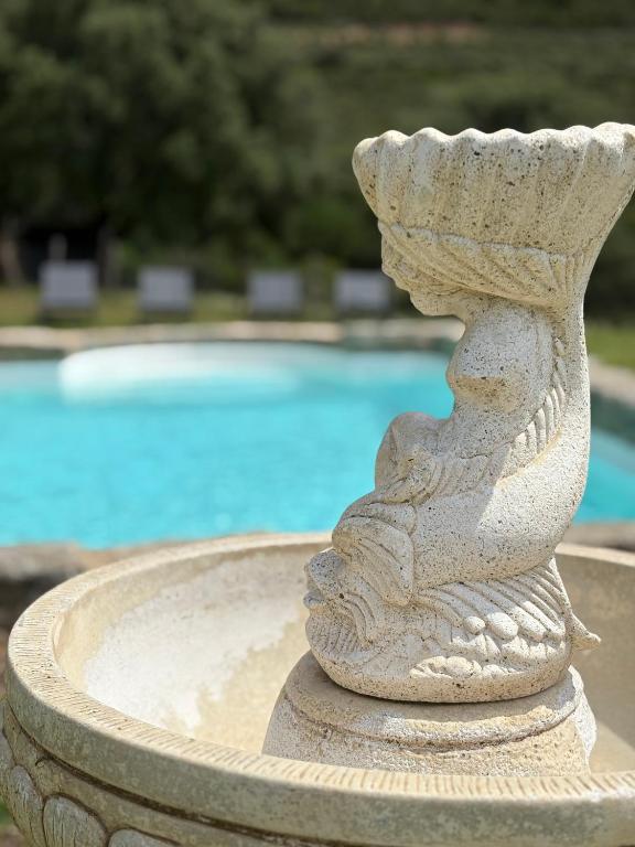 un bain d'oiseaux en pierre devant une piscine dans l'établissement Bergerie de Charme Pedi Lione, à Calvi