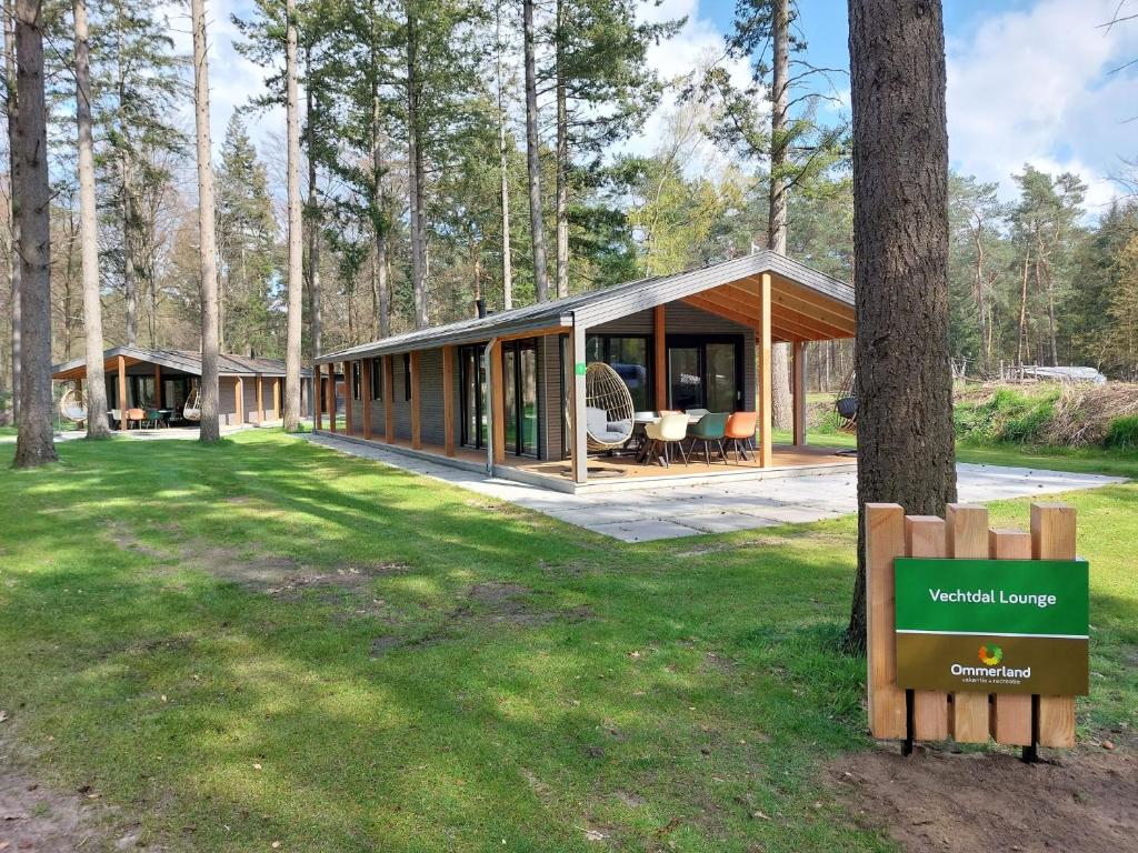una casa nel bosco con un cartello in primo piano di Ommerland a Ommen