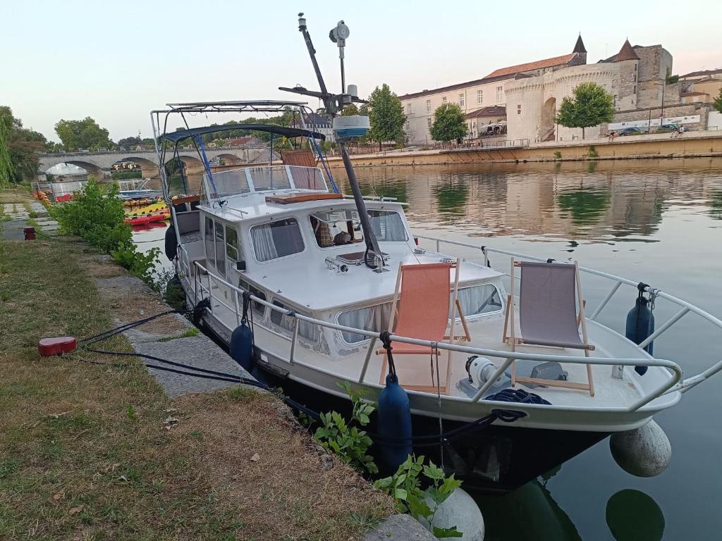 un bateau garé dans l'eau avec deux chaises dessus dans l'établissement Logement insolite, Péniche Hollandaise, à Cognac