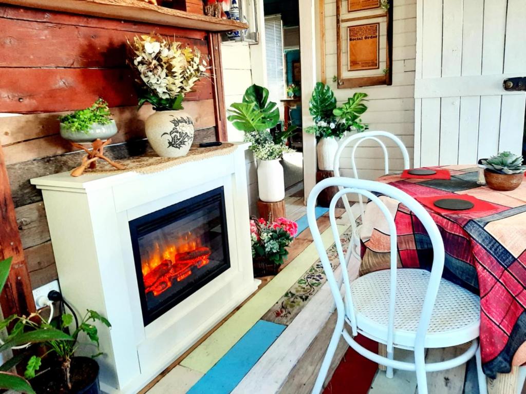 a fireplace on a patio with a table and chairs at Rosewood Cottage -Entire 2 bedroom home with Netflix & WiFi in Tambo