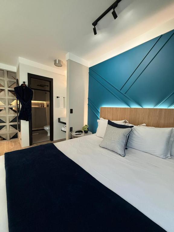 a bedroom with a large bed with a blue wall at Flat Blue Praia de Camburi in Vitória