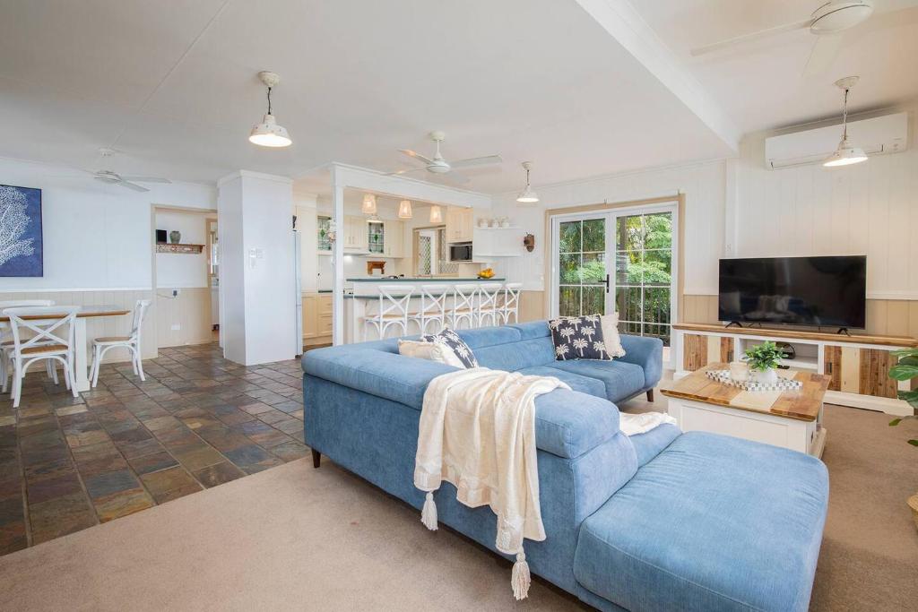a living room with a blue couch and a kitchen at The Lake Haus - Spacious Waterfront Escape with Pool in Karraganbah
