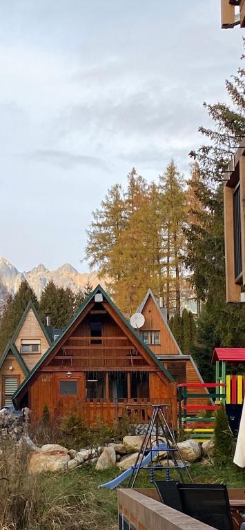 a large wooden house with mountains in the background at Chata TATRY, in Vyšné Hágy