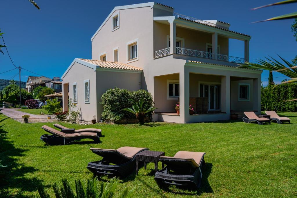 een huis met een gazon met stoelen in de tuin bij Roda Luxury Beach House in Roda