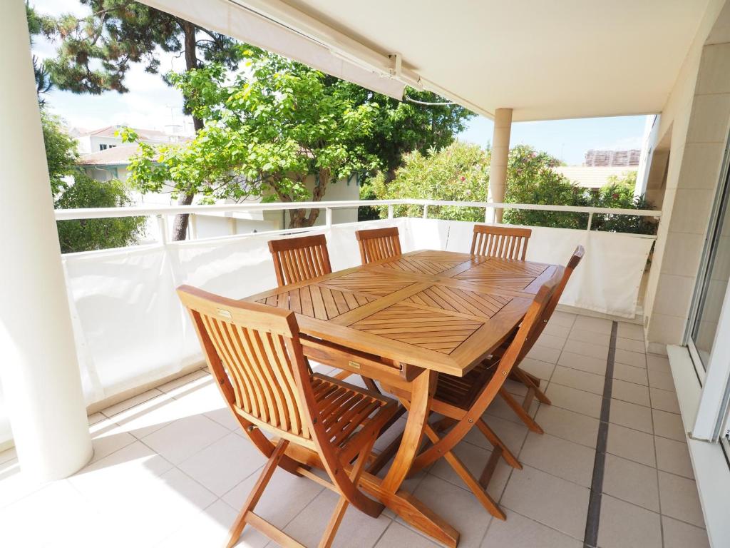 une table et des chaises en bois sur un balcon dans l'établissement Appartement Moderne 6 Pers, Centre d'Arcachon, Parking Sécu, Ascenseur, Ménage Inclus - FR-1-474-97, à Arcachon