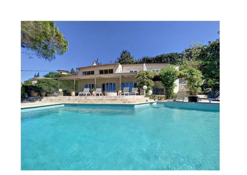 a large swimming pool in front of a house at Charming Villa with stunning sea views in Mougins