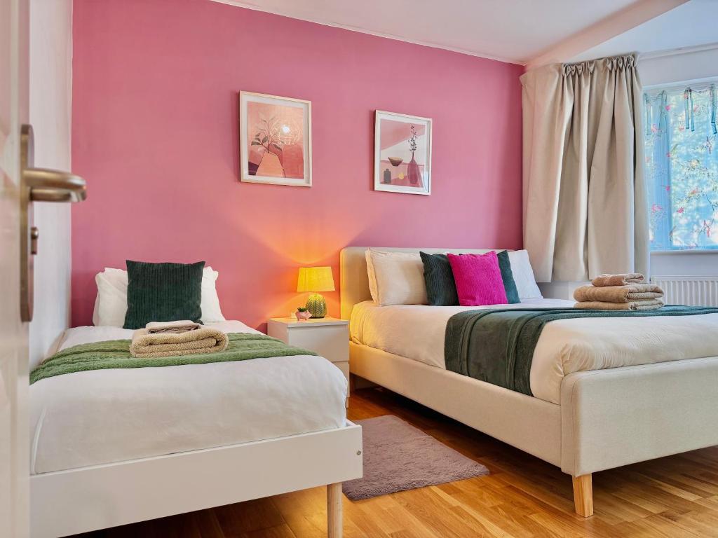 Hotel Modern 1-Bed Apt 30min to Central London & Parking, two beds in a room with pink walls at Modern 1-Bed Apt 30min to Central London & Parking in London