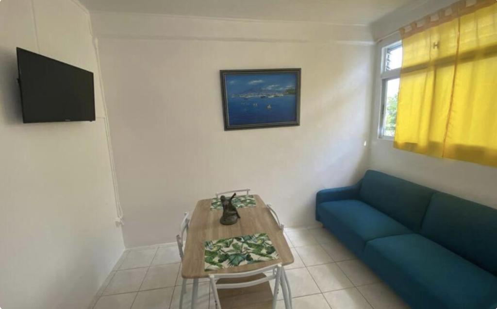 a living room with a blue couch and a table at Appartement Azalée in Fort-de-France