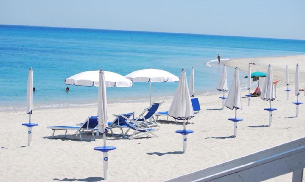 a beach with chairs and umbrellas and the ocean at Solea Village sul mare in San Sostene Marina