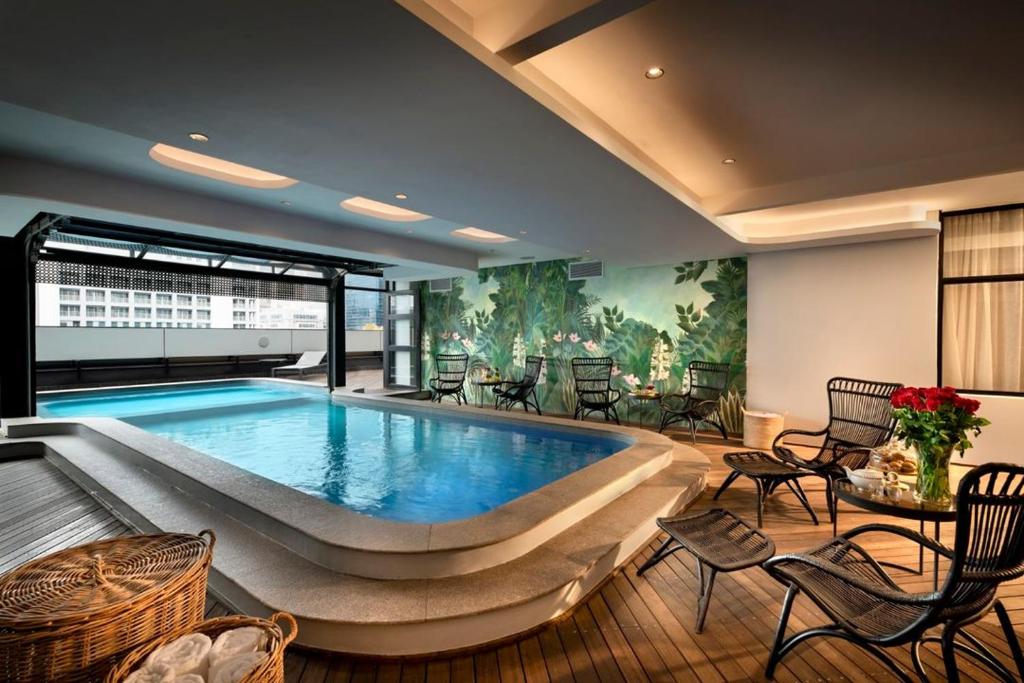 a large swimming pool in a room with chairs and tables at Executive Hotel Apartment at Oynx in Cape Town