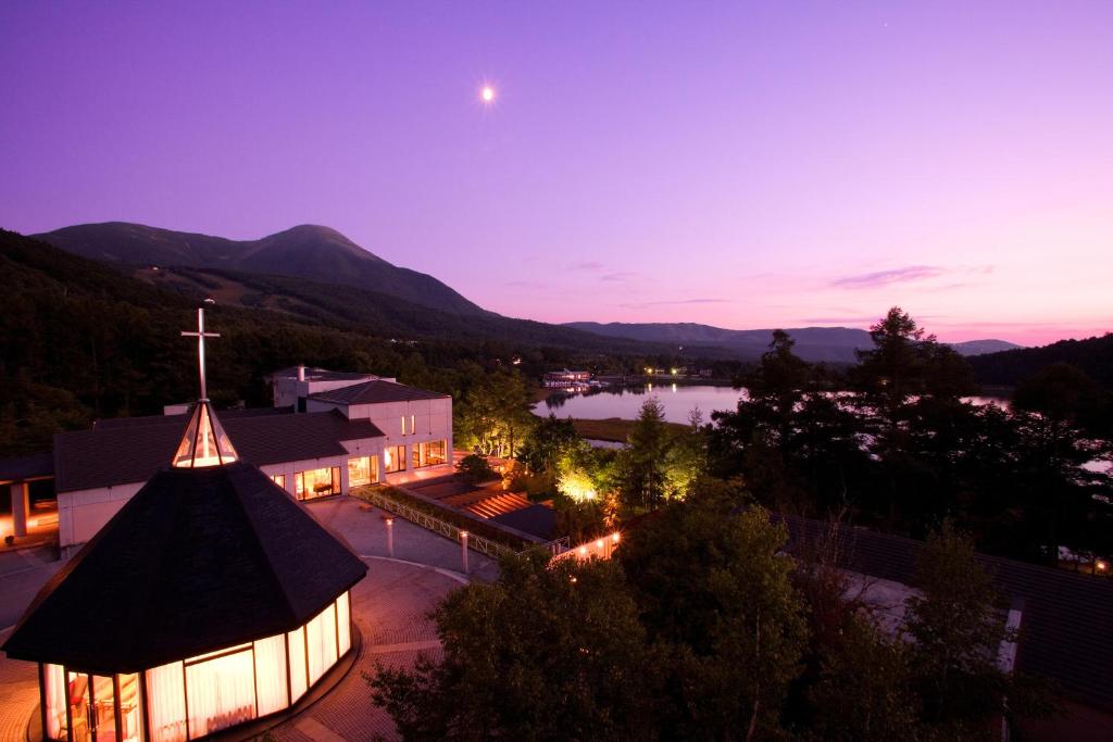 Izumigo AMBIENT Tateshina Hotel في Tateshina: كنيسه مع صليب واطلاله على بحيره