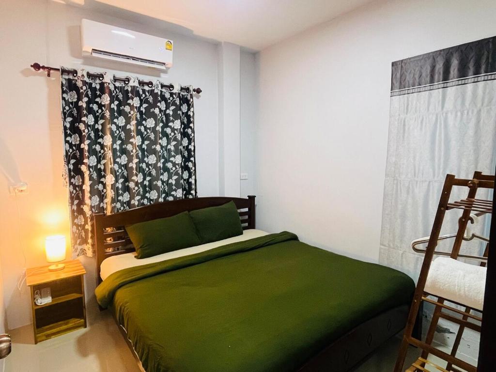 a bedroom with a green bed and a window at บ้าน2ห้องนอนเงียบสงบ15นาทีถึงชายหาด in Ban Khlong Haeng