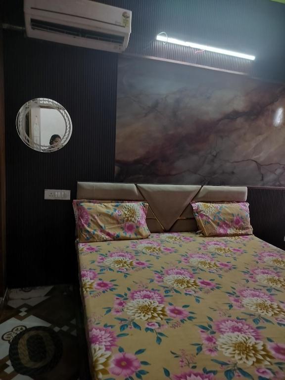 a bedroom with a bed with a floral bedspread and a mirror at Govind dham in Vrindāvan