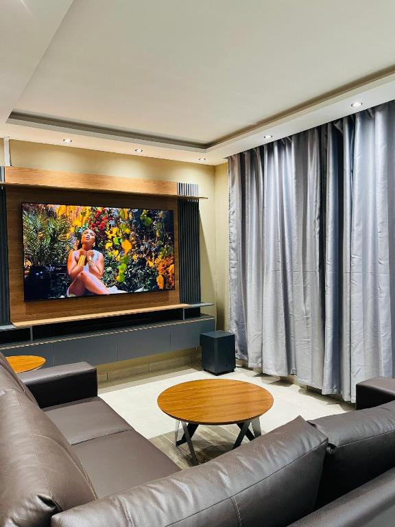 a living room with a couch and a flat screen tv at Que Self Catering Apartments in Gaborone