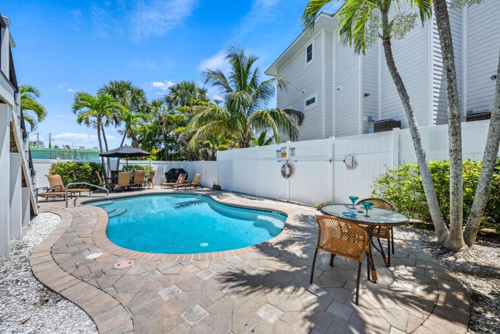 een zwembad met een tafel en stoelen naast een gebouw bij Casita Coconut – Pool, Grill, Pet Friendly, Located in the Heart of SK! in Siesta Key