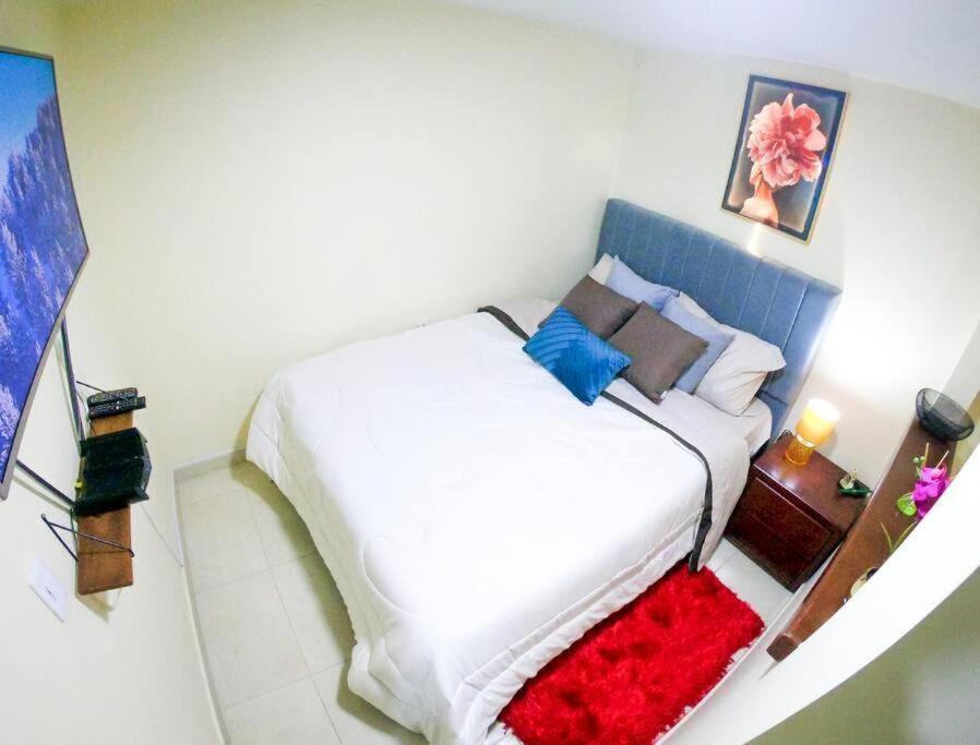 a bedroom with a white bed with a red blanket at Aptos en Suba, Bogotá in Bogotá