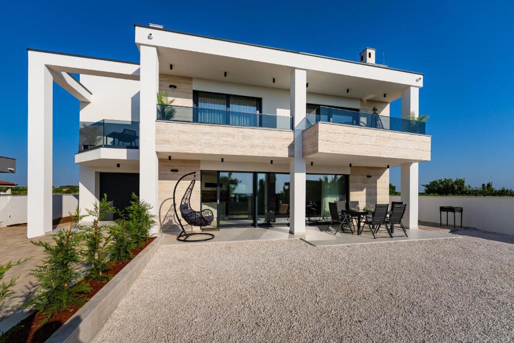 a large white house with chairs and tables at MY DALMATIA - Beach Apartment LaMag in Vrsi