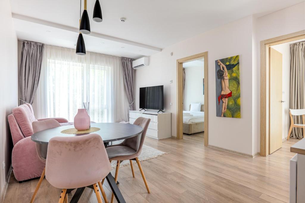 un soggiorno con tavolo, sedie e TV di Mill Central a Palanga