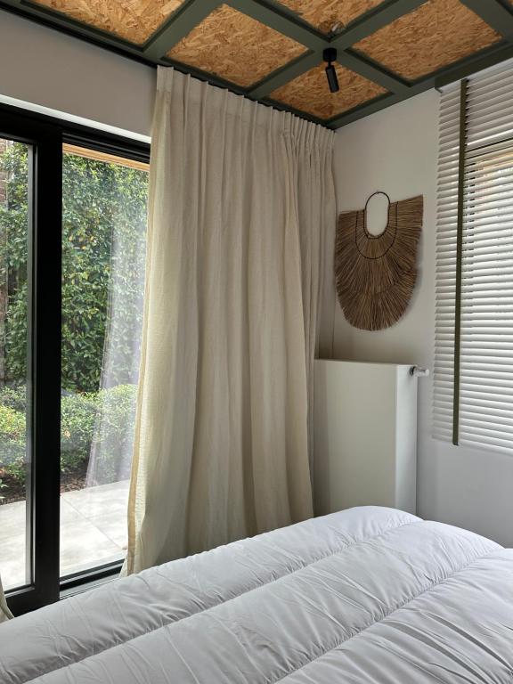 a bedroom with a bed and a large window at DUNE, Maison Littoral by BLOSS stylish apartment with garden and terrace in De Haan