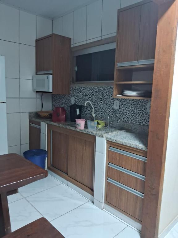 a kitchen with wooden cabinets and a counter top at Casa compartilhada em Itaúnas - Centro da Vila in Conceição da Barra