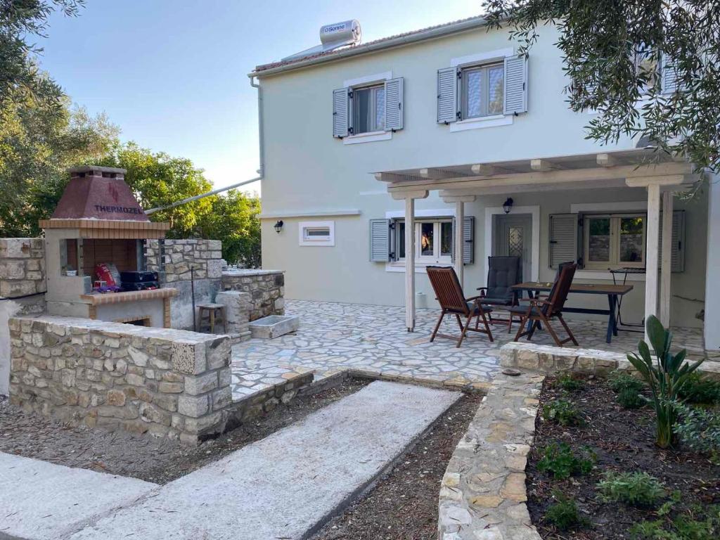 a white house with a patio and a table and chairs at Geropalas Spacious Garden House in Vlachopoulátika