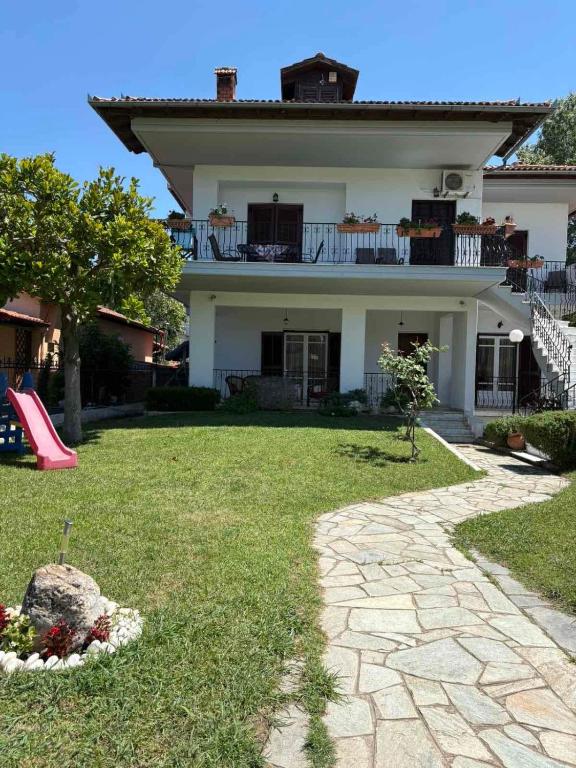 a large white house with a playground in the yard at House by the sea! in Platamonas
